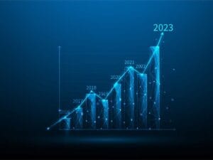 A digital 3D bar chart shows an upward trend from 2016 to 2023. Each year is marked on a bar, with 2023 being the tallest. The graph is set against a blue background, symbolizing growth and progress.