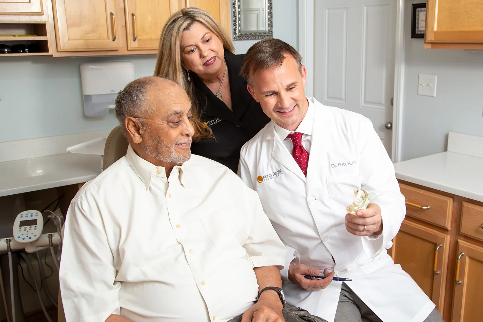 A dentist and his assistant show a patient a