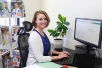 Robyn sitting at her desk smiling at the camera.