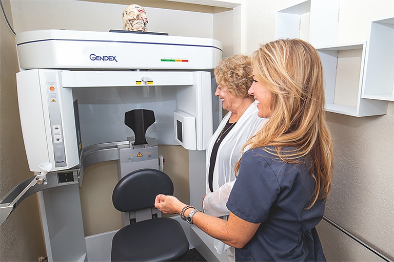 A dental assistant helping a patient at a dental x-ray imaging machine