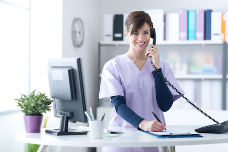 Dental receptionist taking an appointment on the phone.